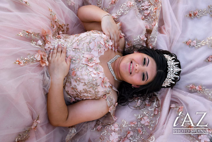 Ideas de uñas para quinceañeras modernas en tendencias 2024 2025 una quinceañera recostada en su vestido sonriendo con sus uñas decoradas